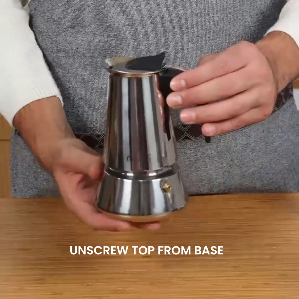 Silver metal Moka Pot held by hands over a wood surface with text unscrew top from base.