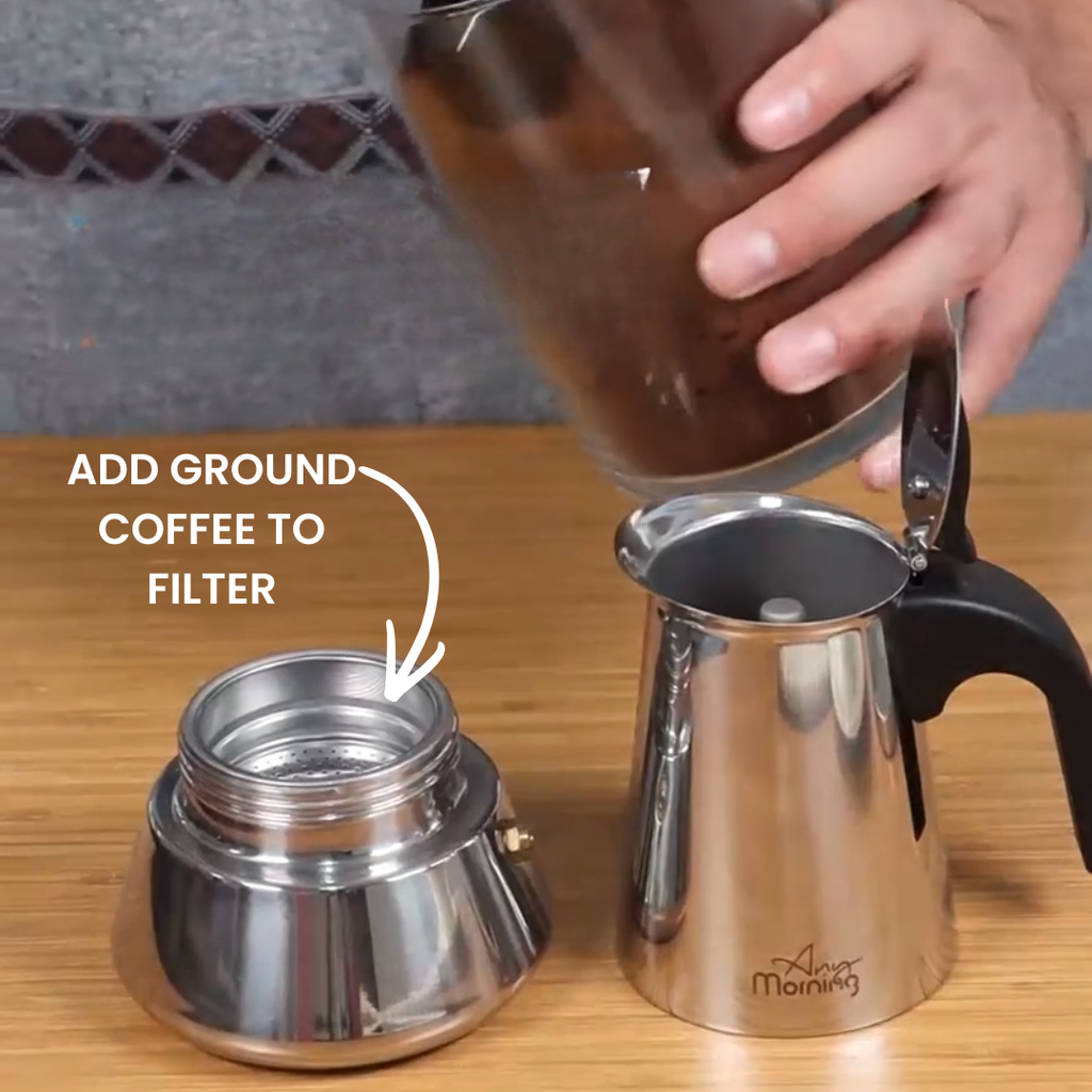 Silver metal Any Morning moka pot disassembled on a wood surface with text reading add ground coffee to filter.