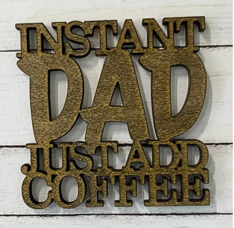Square brown wooden coaster with laser-cut text reading Instant Dad Just Add Coffee.